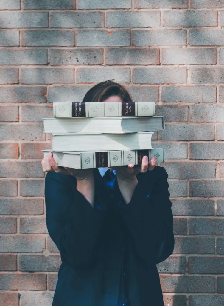 femme tenant quatre livres anciens devant son visage
