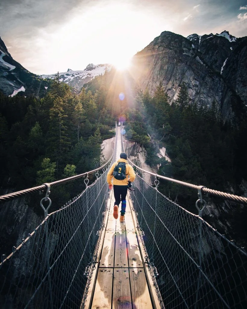 homme courant sur un pont surplombant une grande vallée